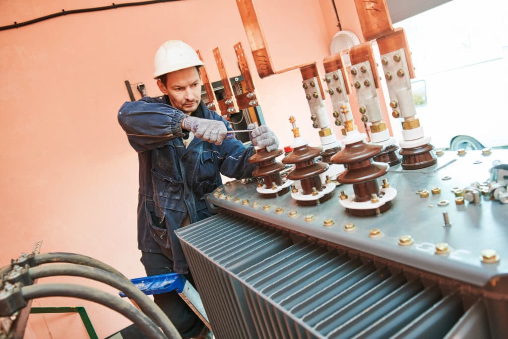 Electrician lineman worker installing power industrial transformer upgrade